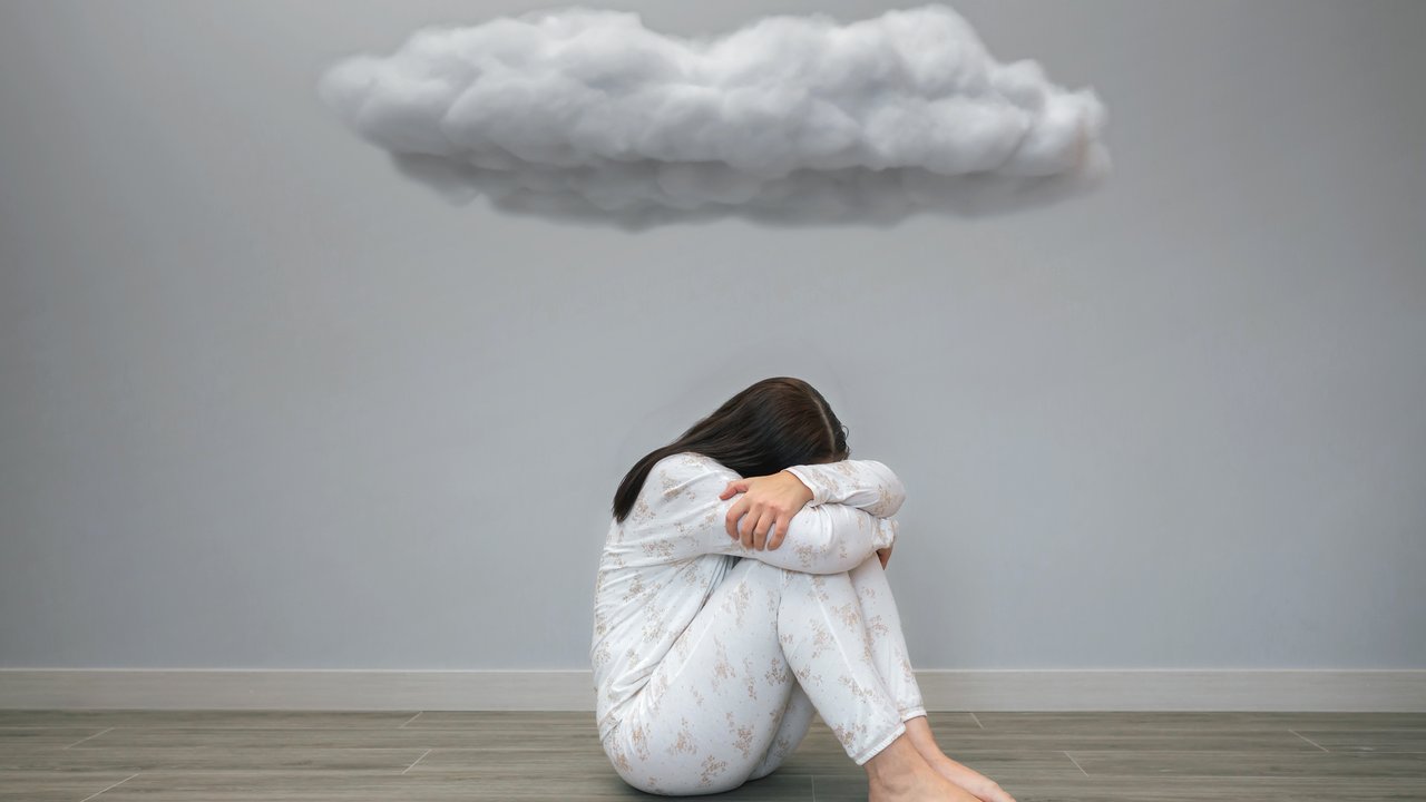 A person sitting beneath a rain cloud