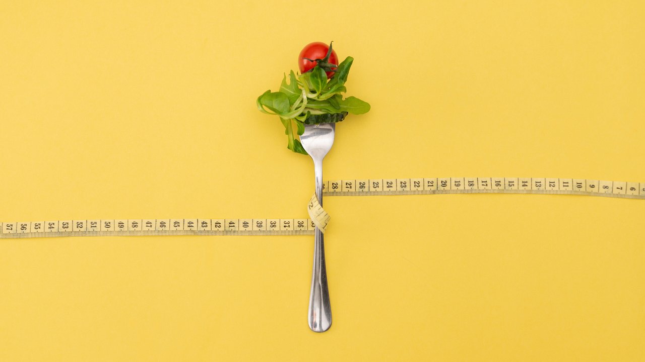 A single forkful of salad beside a measuring tape