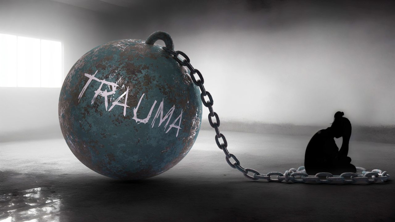 The word trauma on a heavy ball and chain