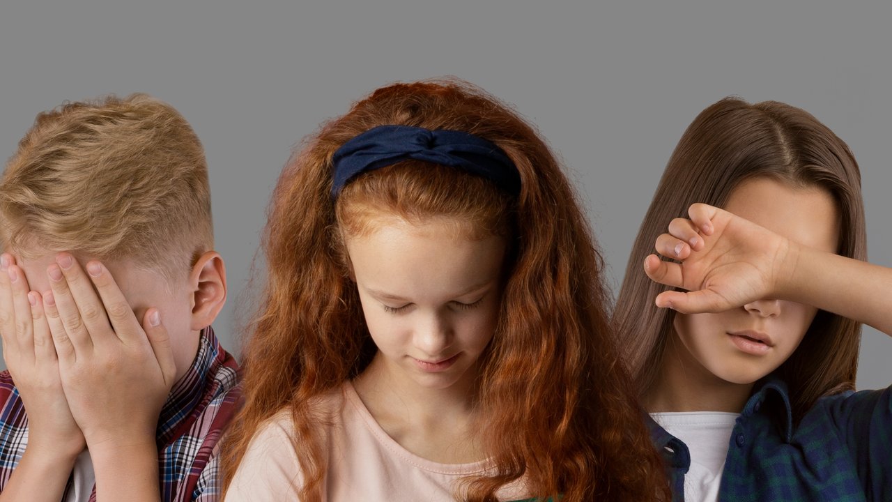 Three children covering their faces
